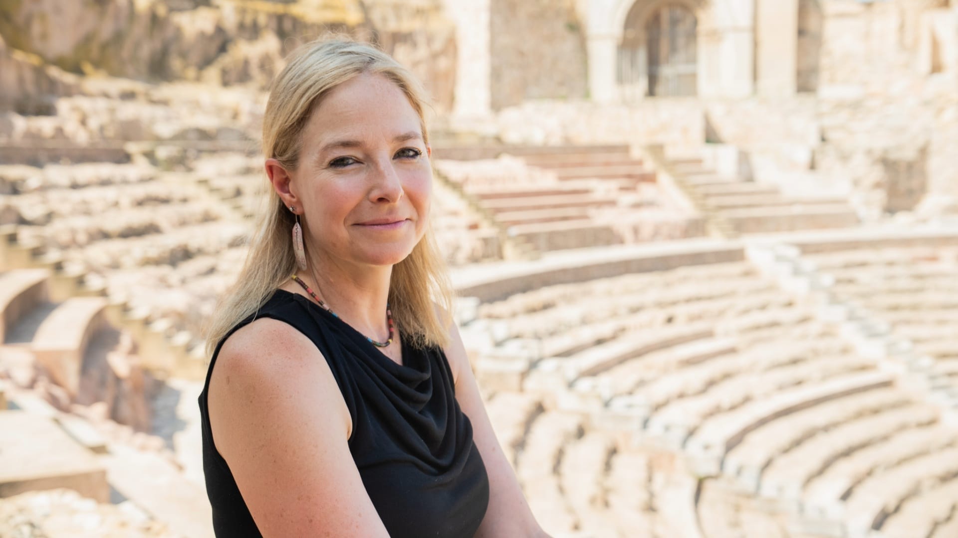 Historian Alice Roberts sitting in a Roman Amphitheatre
